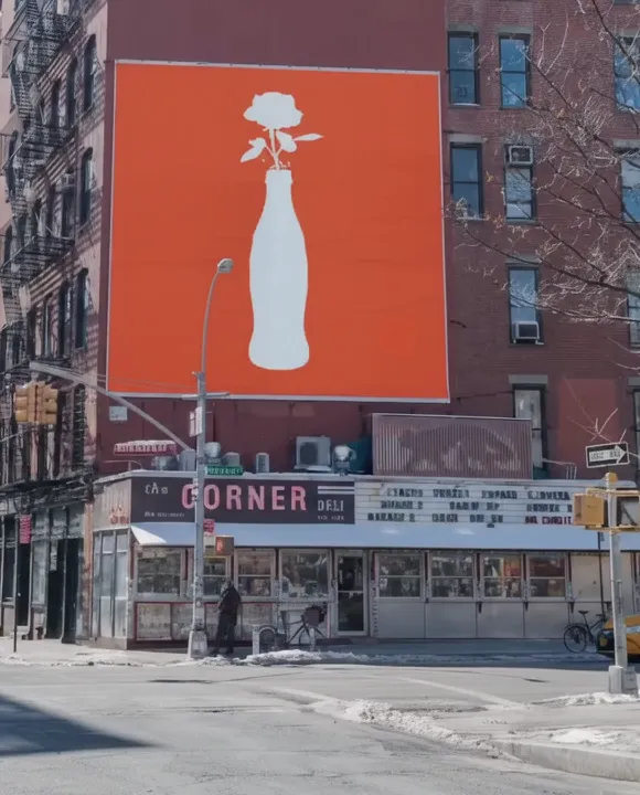 A coral billboard above a New York street corner
